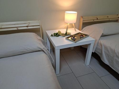 a white table with a lamp on it next to two beds at Camera doppia in San Giuseppe Vesuviano