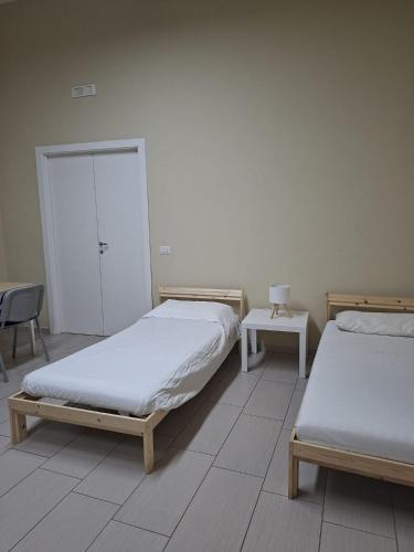 a bedroom with two beds and a table with a chair at Camera doppia in San Giuseppe Vesuviano