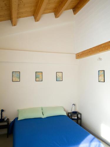 a bedroom with a blue bed and wooden ceilings at Petrikore - Rosso in Scoglitti