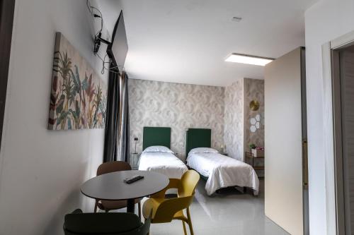 a bedroom with two beds and a table and chairs at Foresteria SMART ROOMS in Viadana