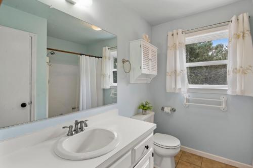 a white bathroom with a sink and a toilet at The Flying Dutchman OBX in Kill Devil Hills