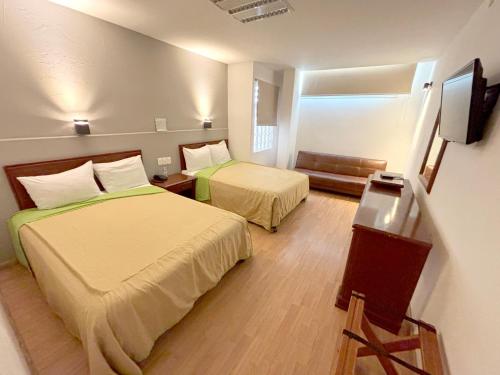 a hotel room with two beds and a television at Hotel Enterprise Inn Plaza in León
