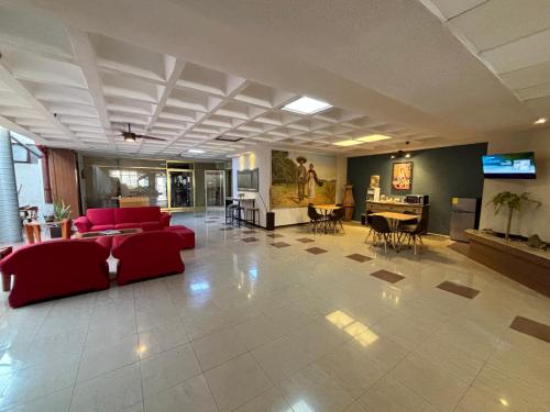 a large living room with red couches and a television at Hotel Enterprise Inn Plaza in León