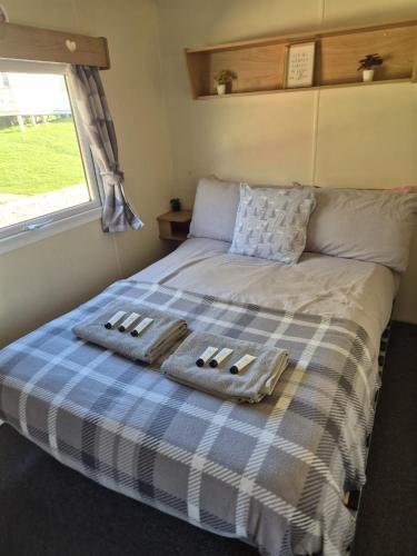 a bed in a small room with a plaid blanket at 3 bedroom caravan 14 kingsgate in Shanklin