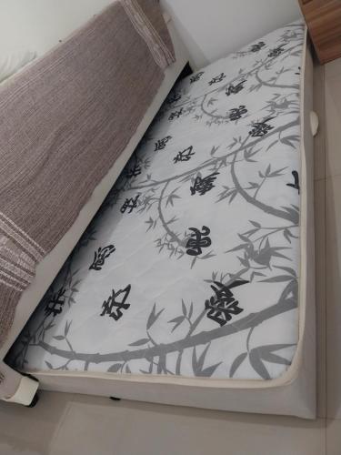 a bed with a black and white bedspread at Kitnet no Centro Garagem, ar e Wi-Fi in Itaperuna