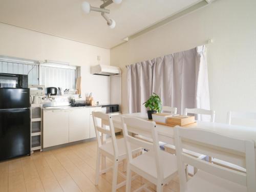 a kitchen with a white table and white chairs at Kanigaya House in Kawasaki