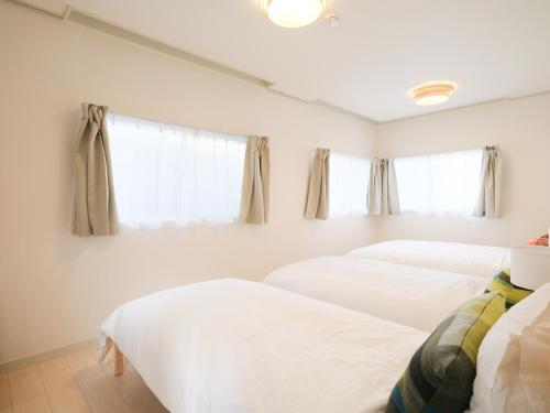 two beds in a room with two windows at Kanigaya House in Kawasaki