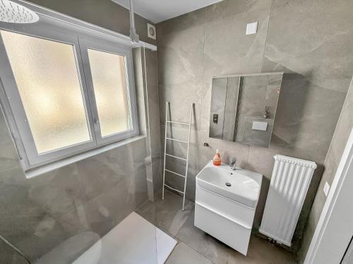 a bathroom with a white sink and a mirror at Appartamento Rivamaggia Locarno in Solduno