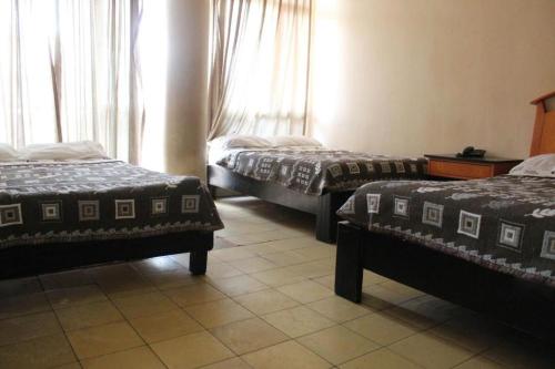 a hotel room with two beds and two windows at Hotel Regis in Monterrey