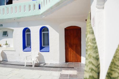 a white house with blue windows and a wooden door at Hotel OM Tangolunda in Tangolunda