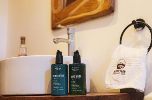 a bathroom counter with two bottles of shampoo and a sink at Amboseli Discovery Camp in Amboseli