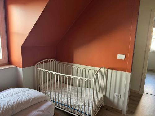 a crib in a room with an orange wall at Noordzeehuys in Middelkerke