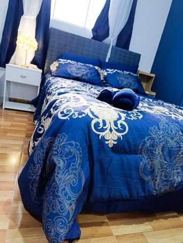 a blue bed with blue and white sheets and pillows at Unique garden deluxe apartment in Trujillo