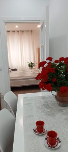 a table with two cups and a vase of red flowers at Cinghiale Bianco in Cagliari