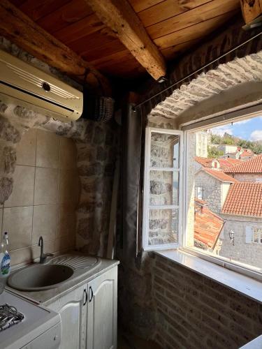 eine Küche mit Spüle und Fenster in der Unterkunft Apartments Gudco in Perast