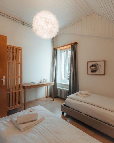 a bedroom with two beds and a desk and a chandelier at LaVida LakeSoul Cozy Retreat in Murten am See & Altstadt, free parking in Murten