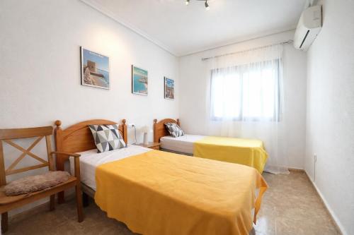 a bedroom with two beds and a chair and a window at Panoramic Sea View Cabo Roig in Orihuela Costa