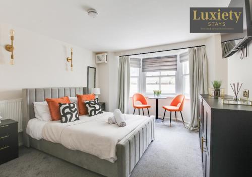 a bedroom with a bed with orange chairs and a table at New! Stunning Studio City Centre Nr High Street in Southend-on-Sea