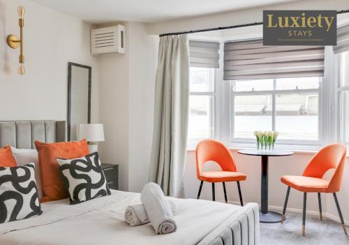 a bedroom with a bed with orange chairs and a table at New! Stunning Studio City Centre Nr High Street in Southend-on-Sea