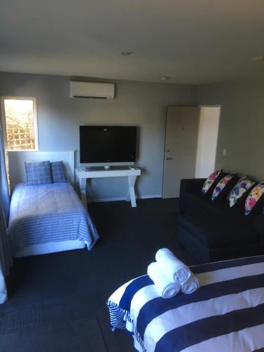 a bedroom with a bed and a tv and a couch at Sandy Feet Accommodation in Christchurch