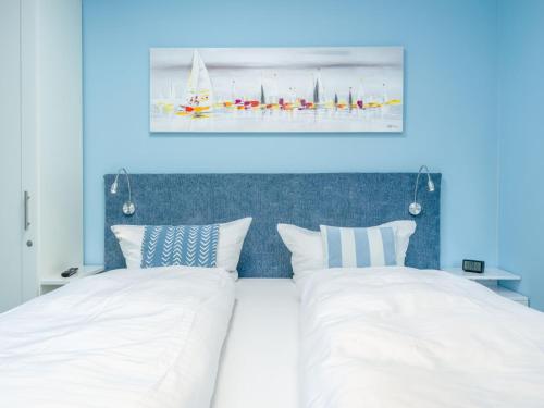 a bedroom with two white beds and a blue wall at See Lün 4 Sterne TOP-Fewo in Westerland Sylt strandnah zentral mit Balkon Sauna in Westerland