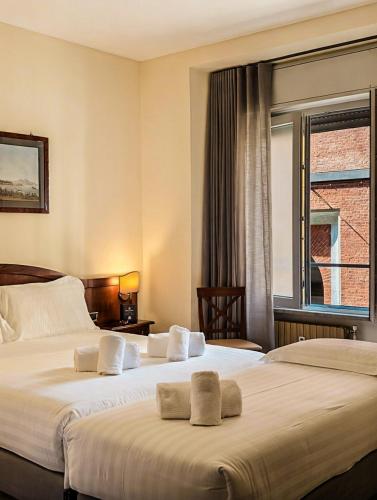 two beds in a hotel room with a window at Hotel Pavone in Milan