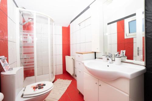 a red and white bathroom with a sink and a toilet at Alex house in Kouramaditika
