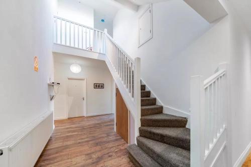 a staircase in a home with white walls and wood floors at Park 1 in London