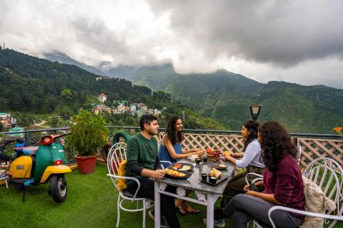 a group of people sitting at a table on a balcony at PACK Mcleodganj in McLeod Ganj