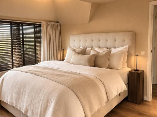 a bedroom with a large bed with white sheets and pillows at Villa Verano in Noordwijk aan Zee