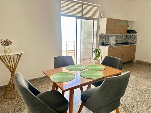 a dining room table with green chairs and a kitchen at APARTAMENTO COMPLETO, Piedra viva in Zapatoca
