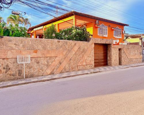 a house with a stone wall next to a street at Terra do Sol Pousada e Hostel in Porto Seguro