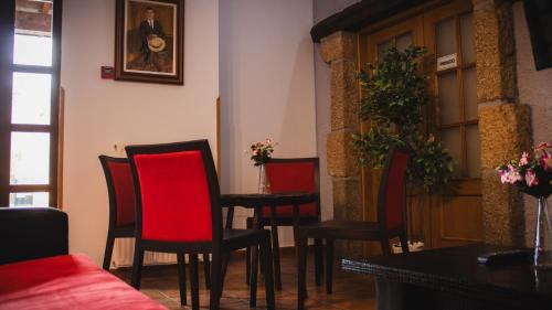 a dining room with red chairs and a table at Hotel El Angliru in Cangas de Onís
