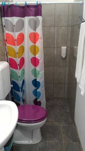 a bathroom with a toilet with a colorful shower curtain at vila gira odeceixe in Odeceixe