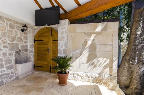 a room with a stone wall with a door and a tv at Villa Strnj in Živogošće