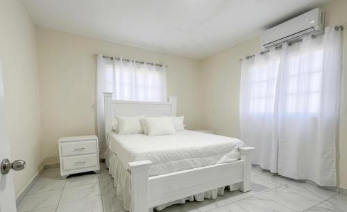 a white bedroom with a white bed and a window at Balbuena Countryside Villa with Private Pool in San Felipe de Puerto Plata