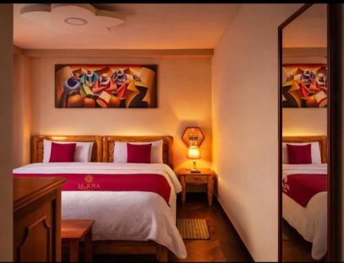 a bedroom with two beds and a painting on the wall at Hotel LaJoya in Otavalo
