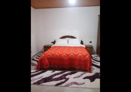 a bedroom with a bed with a red comforter at Shpija E AMEL (Sweet Guest House) in Ferr-Shkopet