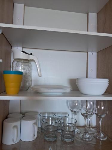 a shelf filled with glasses and plates and a mixer at Sunset Ocean View Apartment in Flic-en-Flac