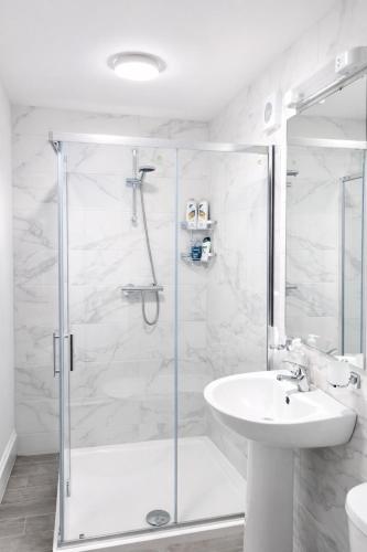 a white bathroom with a shower and a sink at Aran View Holiday Homes - The Courtyard Suite - Cozy for two in Doolin