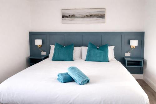 a white bed with blue pillows and two blue pillows at Aran View Holiday Homes - The Courtyard Suite - Cozy for two in Doolin