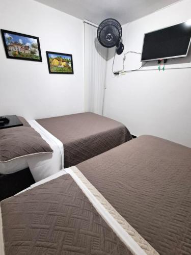 a room with two beds and a flat screen tv at Apto Rincón del Café -"Piscina-Parking-8min Parque Café 321-435-21-00" in Montenegro