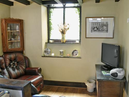 a living room with a leather chair and a television at Gamekeepers Cottage - Hw7729 in Llangadog