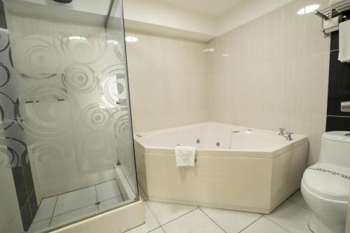 a bathroom with a shower and a tub and a toilet at Hotel Britania Miraflores in Lima