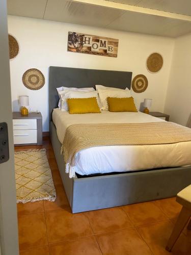 a bedroom with a large bed with yellow pillows at Casinha em frente à Lagoa in Aldeia de Brescos