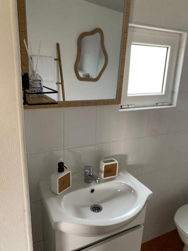 a white bathroom with a sink and a mirror at Casinha em frente à Lagoa in Aldeia de Brescos