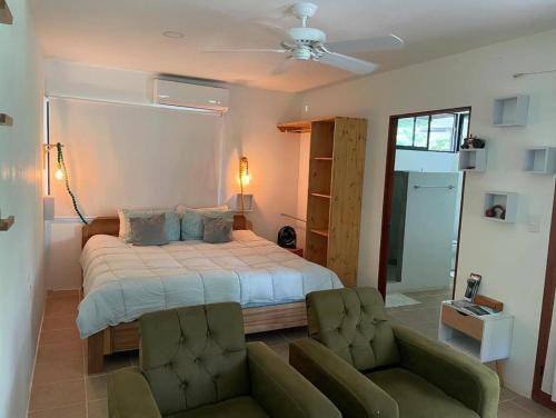 a bedroom with a large bed and two chairs at Playa Negra Art House in Hone Creek