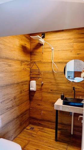 a bathroom with a wooden wall with a sink and a mirror at Canto Flix in Brasília