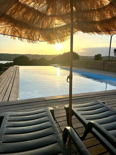 a view of a pool with an umbrella and chairs at Monte da Tojeirinha in Montargil