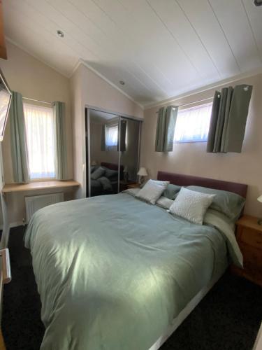 a bedroom with a large bed with green sheets and pillows at Sunset Lodge in Poole